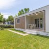 Unità abitativa moderna con veranda nel verde e sentiero d’ingresso.