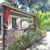 Bungalow in legno con veranda, tendine rosse e piante intorno.
