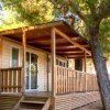 Casa mobile con veranda di legno, situata sotto grandi alberi.