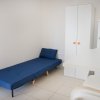 Interno minimalista con letto blu, armadio bianco e angolo bar con sgabelli.