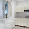 Cucina luminosa con tavolo, sedie pieghevoli e angolo cottura con armadietti chiari.