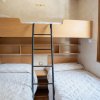 Camera con letto a castello, due letti sotto e scaffali. Finestra a destra.