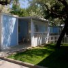 Bungalow blu con veranda ombreggiata e cortile verde.