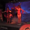 Spettacolo su palco con persone in costumi rossi e luci soffuse.