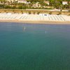 Spiaggia sabbiosa con ombrelloni allineati e mare calmo.