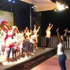 Bambini e animatori danzano su un palco al chiuso.