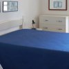 Camera da letto con coperta blu e finestre aperte.