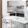 Cucina moderna con tavolo e sedie bianche.