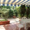 Un patio coperto con tavolo e sedie in plastica, circondato da piante e vasi su piastrelle.