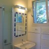 Bagno con doccia in vetro, specchio con piastrelle blu e finestra.