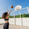 Donna tira a canestro su campo da basket esterno.