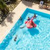 Persone su gonfiabile rosa in piscina.