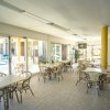 Sala da pranzo luminosa con tavoli e sedie vicino a grandi finestre.