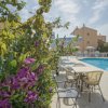 Giardino con cespugli di fiori viola accanto a una piscina con sedie e tavoli.