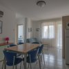 Soggiorno con tavolo e sedie blu, divano, frigorifero, quadro e aria condizionata.