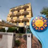 Esterno di un hotel giallo con insegna e giardino.