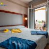 Camera d'hotel con letto matrimoniale e balcone con una famiglia al tavolo.