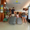 Una famiglia con valigie entra in un hotel, vicino a un frigorifero con bevande.