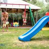 Un uomo gioca con un bambino nel parco giochi accanto a uno scivolo blu.