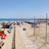 Una spiaggia con ombrelloni, giocattoli per bambini e persone che si rilassano al sole.