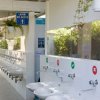 Lavandini con segni di uso corretto, piante sospese e cartelli in un'area bagno esterna.