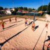 Persone giocano a beach volley su un campo sabbioso all'aperto.