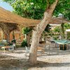 Giardino con tavoli, sedie e amache appese tra gli alberi.