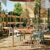 Tavolo all'aperto con sedie in un giardino, circondato da piante rampicanti su grigliati di legno.