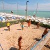 Persone giocano a beach volley su un campo di sabbia vicino al mare.
