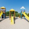 Gioco per bambini con tre scivoli gialli su una superficie sabbiosa.