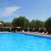 Grande piscina all'aperto con lettini e ombrelloni arancioni.