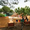 Parco giochi con strutture di legno e alberi verdi circostanti.