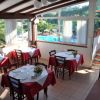 Una sala da pranzo luminosa con tavoli apparecchiati, vista su una piscina attraverso le finestre.