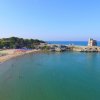 Spiaggia con torre antica e mare calmo.