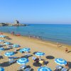 Spiaggia affollata con ombrelloni blu e mare.