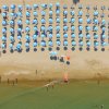 Ombrelloni blu su una spiaggia sabbiosa affollata.
