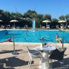 Persone nuotano in piscina, tavoli e sedie in primo piano.