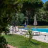 Piscina con lettini e ombrelloni, circondata da alberi.