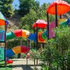 Un colorato parco giochi con scivoli e altalene tra alberi e cespugli.