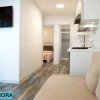 Interno moderno con divano, TV a muro e cucina accogliente.