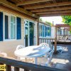 Veranda in legno con tavolo bianco e sedie, affacciata su giardino.