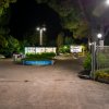 Entrata notturna di un centro vacanze, con luci e cartelloni illuminati tra alberi.
