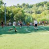 Partita di calcetto su un campo circondato da alberi e spettatori.