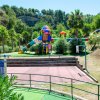Un parco giochi colorato con scivoli e altalene immerso nel verde.