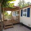 Esterno di una casa mobile con veranda in legno e finestre blu.