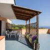 Terrazza con tavolino, sedie, fioriere e vista mare.