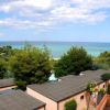 Panorama con tetti di edifici, alberi e mare all'orizzonte.