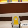 Due letti singoli con cuscini marroni e orologio giallo.
