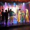 Una scena teatrale con attori in costumi colorati su un palco illuminato.