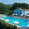 Una piscina circondata da ombrelloni e alberi, con una casa blu sullo sfondo.